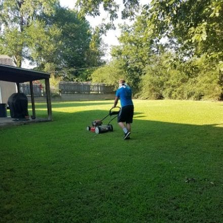A male employee mowing grass.