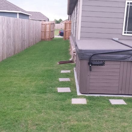 A neatly kept backyard. The grass is green and evenly mowed.