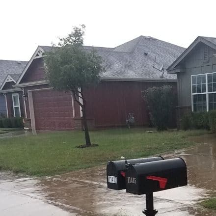 Rain falls on a front yard, preventing it from being mowed.