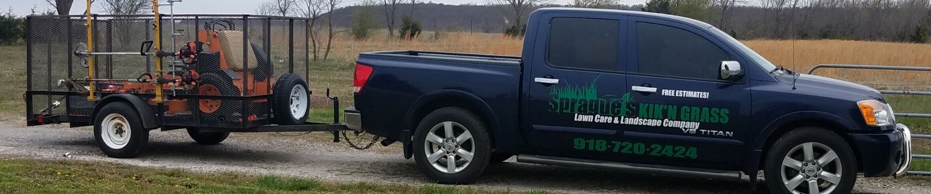A black work truck with Sprague's Kik'N Grass logo printed on the sid. The truck is hauling a trailer carrying a large lawn mower.